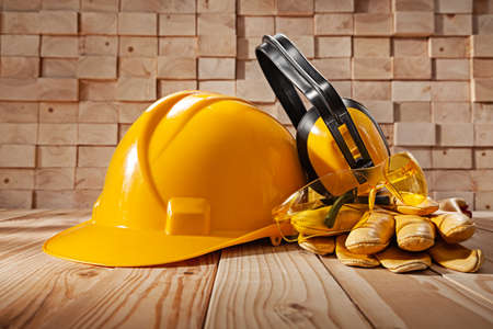 Construction Safety Tools Concept. Yellow Helmet Protective Earphones Goggles Leather Gloves On Wooden Beams Stackの写真素材