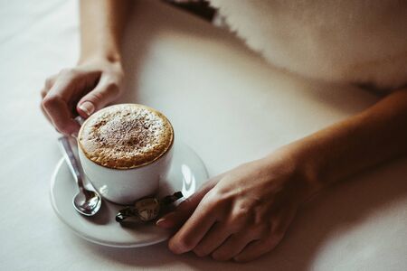 women's hands next to coffee cappuccinoの写真素材