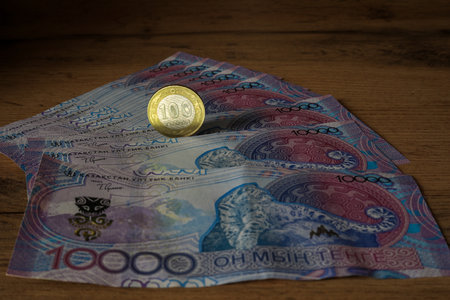 100 tenge coin on a background of 10,000 tengeの写真素材