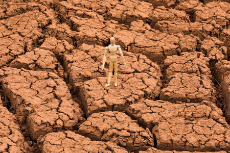 Wooden man figurine on cracked earth background, closeup of photoの写真素材