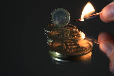 Coins and burning match on a black background, close-upの写真素材