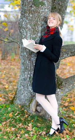 Young student girl is studying outside near the treeの写真素材