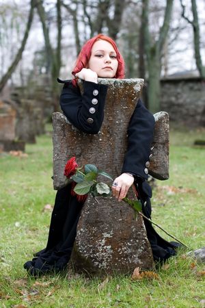 Gothic girl with a rose on a cemeteryの写真素材