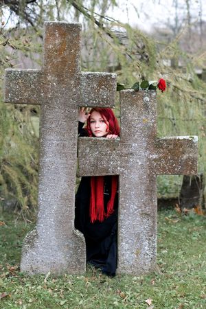 Gothic girl with a rose on a cemeteryの写真素材
