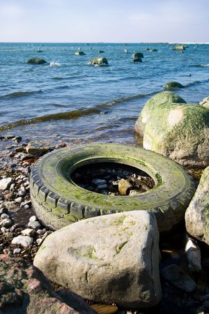 Old tyre polluting a seashore due to insufficient recyclingの写真素材