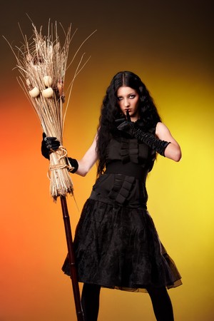 Halloween witch with a broom over color backgroundの写真素材