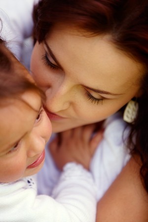 Young attractive mother is kissing her naughty little girlの写真素材