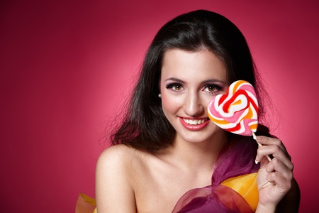 Portrait of a girl holding lollypop over pink backgroundの写真素材