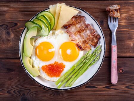 Top view of ketogenic diet breakfast on the white plate with a fork on dark wooden background.の写真素材