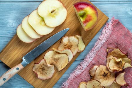 Top view of apple chips and fresh-cut apple with the knife on a wooden backgroundの写真素材