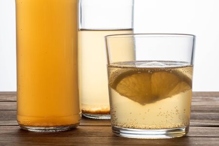 Two bottles and glass of kombucha drink on a wooden table with lemon. Soft focus.の写真素材
