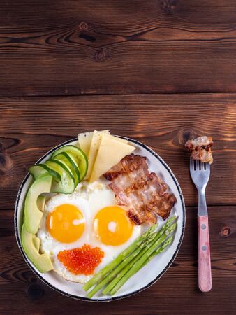 ketogenic diet breakfast on the white plate with a fork on dark wooden background with copy spaceの写真素材