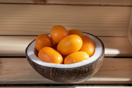 Close up view kumquat in a coconut bowl on wooden background.の写真素材