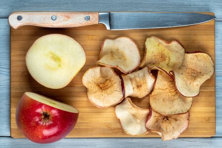 Top view of apple chips and fresh-cut apple with the knife on a wooden backgroundの写真素材