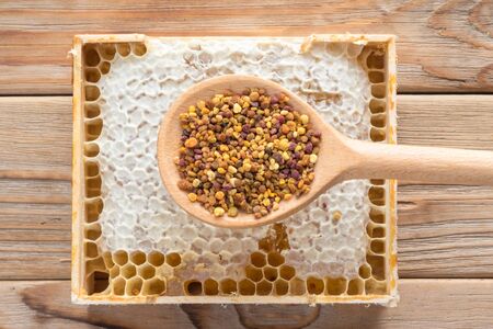 The wooden spoon of bee pollen with honeycombs on wooden backgroundの写真素材