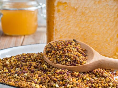 Close up view of the wooden spoon of bee pollen with honeycombs on wooden background. Selective focusの写真素材