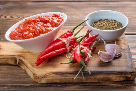 Close up view of a sauceboat of harissa with hot chili pepper and garlic and cumin seeds on a white linen towel. Soft focus.の写真素材