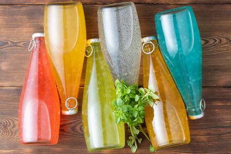 Six bottles of Basil Seed with basil leaves on a wooden background. Red, yellow, light blue and green color. Flat layの写真素材