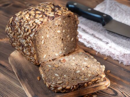 Close up View of Brown Homemade Bread with knife on wooden background.の写真素材