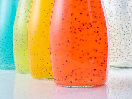 Close up view of bottles of Basil Seed beverage. Red, yellow, light blue and green color. Soft focus.の写真素材