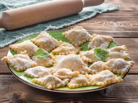 Perspective View of Fresh Homemade Ravioli on Wooden Background With Rolling Pin and Circular Knife. Soft focus.の写真素材