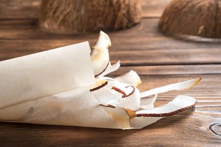 Close up view of dried coconut chips in a paper on wooden backgroundの写真素材