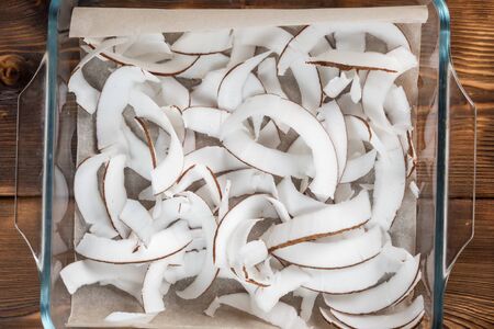 Top view of dried coconut chips in on baking paper in a glass panの写真素材