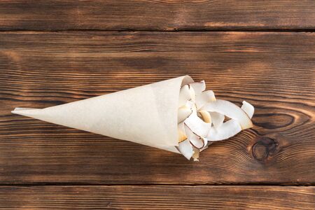 Dried coconut chips in a paper on wooden backgroundの写真素材