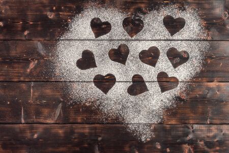 Top view of Shapes of hearts on flour on wooden background. With copy space.の写真素材