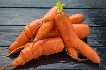 fresh ugly carrots on black wooden backgroundの写真素材