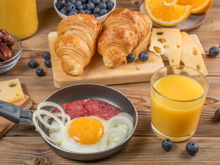 Close up view of a Continental Breakfast with Croissants and Fried Eggs and orange juice and coffee and cheese on wooden background.の写真素材