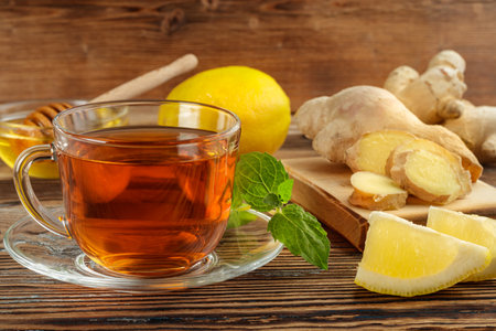 Ginger tea with lemon and mint in a glass cup on an old wooden table with ingredients.の写真素材