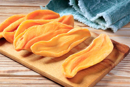 Close-up view of dried mango slices on a wooden board.の写真素材