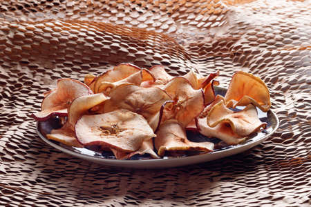 Dried apple chips in rustic plate. Selective focus.の写真素材