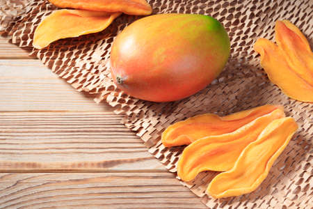 Close-up view of dried mango slices on a wooden background with mango.の写真素材