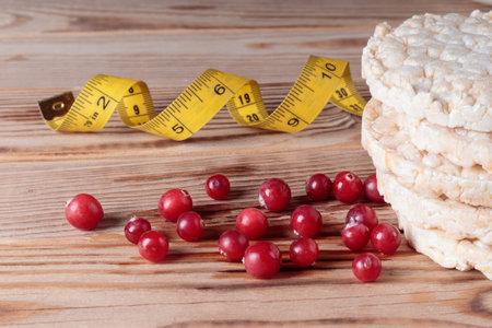 Red cranberry and crispbreads and tape measure on wooden background.の写真素材