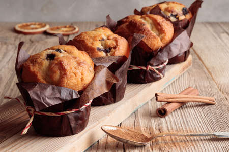 View of four homemade delicious muffins and cinnamon on wooden backgroundの写真素材