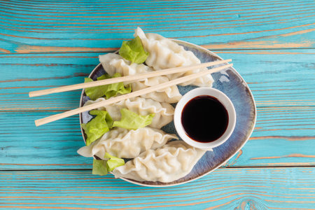 Fresh boiled Chinese dumplings with soy sauce on blue wooden background.の写真素材