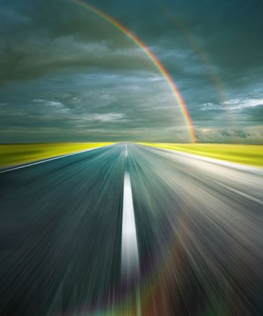 Storm clouds with rainbow and asphalt road with reflection of rainbowの写真素材