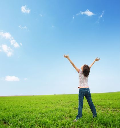 Young woman standing on a meadow's green grassの写真素材