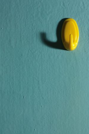 Yellow hook on wall with shadowの写真素材
