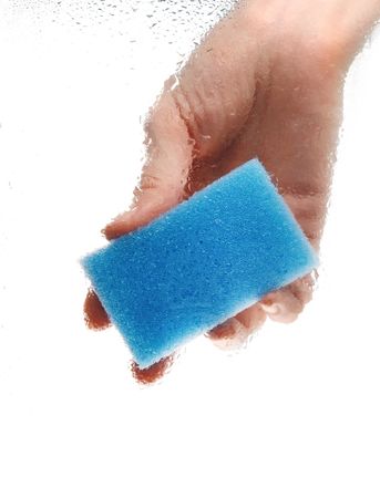 Blue sponge in hand on wet glass surface