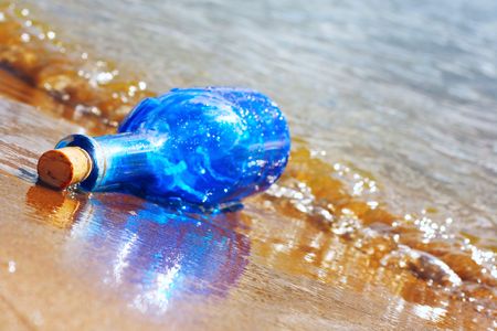 Blue glass bottle on wet sandの写真素材