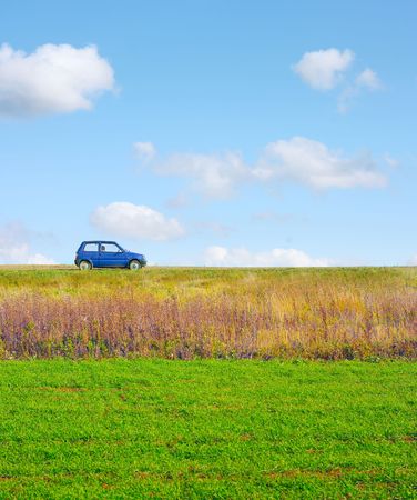 Little car on a road near meadow with green grassの写真素材