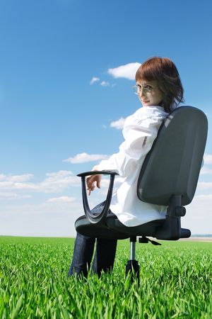 Woman on chair in green fieldの写真素材