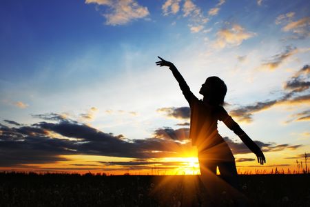 Young women doing exercises on field with grass under sunset lightの写真素材