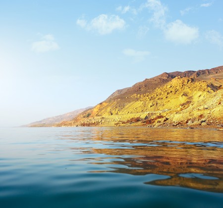 Sea with waves and mountain under sunset lightの写真素材