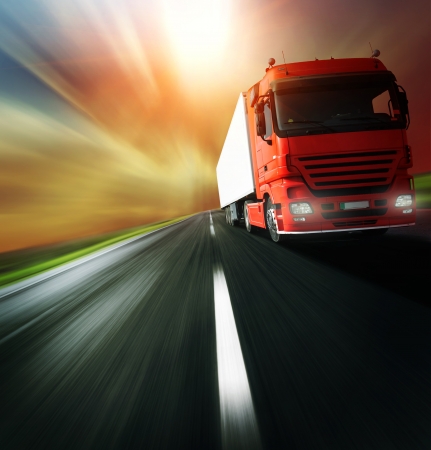 Red truck on blurry asphalt road over cloudy sky backgroundの写真素材