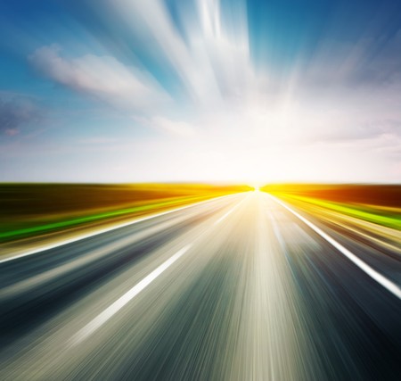 Empty asphalt blurry road with cloudy sky and sunlightの写真素材