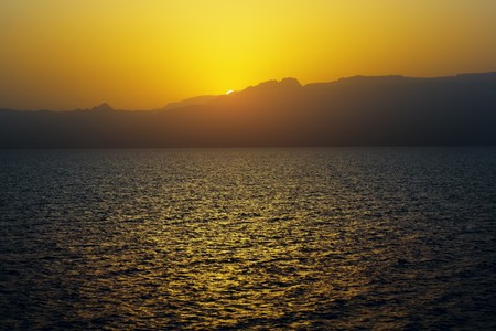 Sunset over sea and mountainsの写真素材